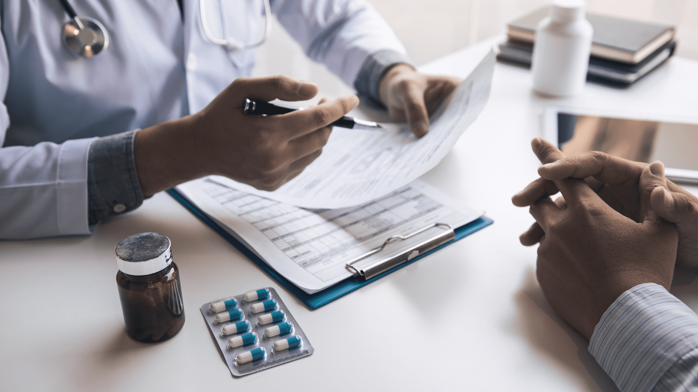 Psychiatry resident speaking with a patient, medicine bottles on the table in between them.